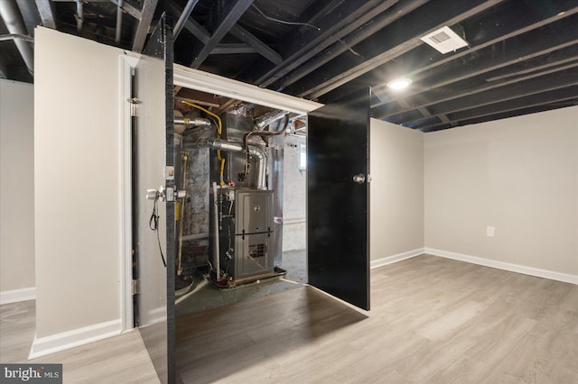 basement with heating unit and hardwood / wood-style flooring