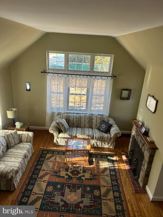 living room featuring a fireplace, vaulted ceiling, and dark wood-type flooring