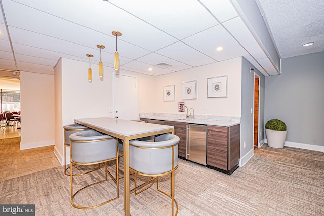 bar with light carpet, sink, refrigerator, and hanging light fixtures