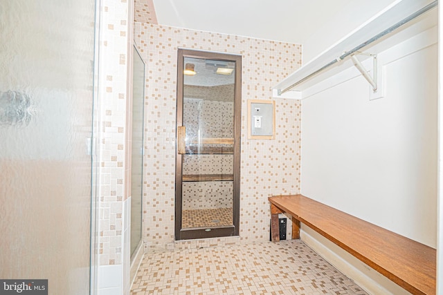 bathroom with a shower with door and tile walls