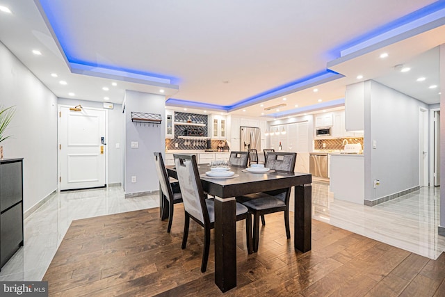 dining space featuring light hardwood / wood-style floors and a tray ceiling