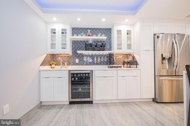 bar featuring stainless steel refrigerator with ice dispenser, white cabinetry, beverage cooler, and decorative backsplash