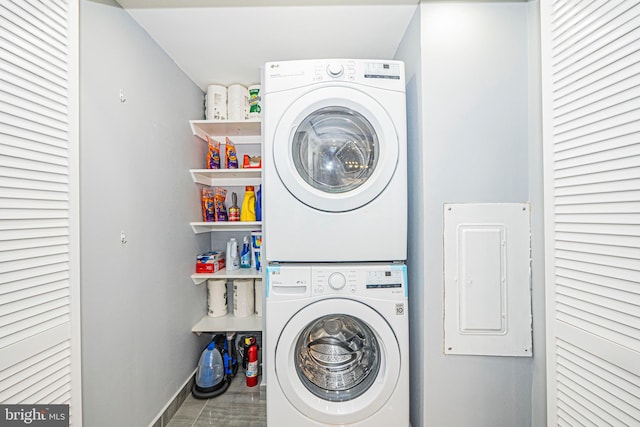 washroom featuring electric panel and stacked washer and clothes dryer