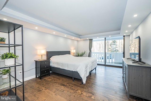 bedroom with a wall of windows, a raised ceiling, and dark hardwood / wood-style flooring