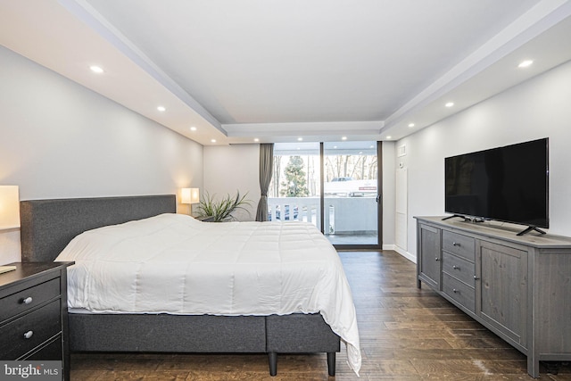 bedroom featuring a tray ceiling, dark hardwood / wood-style flooring, and access to outside