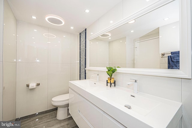 bathroom with vanity, toilet, tile walls, and wood-type flooring