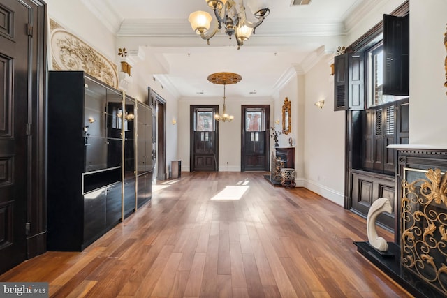 foyer entrance featuring dark wood-type flooring, a wealth of natural light, a chandelier, and ornamental molding