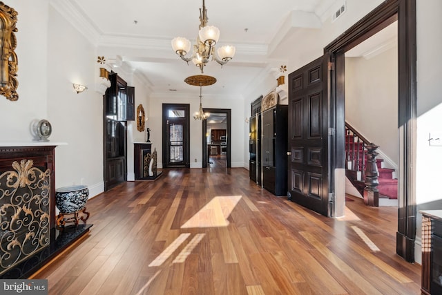 interior space featuring an inviting chandelier, ornamental molding, and wood-type flooring