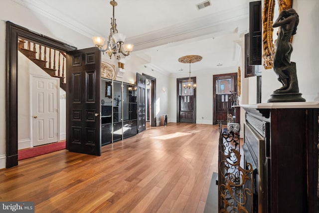 interior space featuring pendant lighting, hardwood / wood-style floors, crown molding, and a chandelier