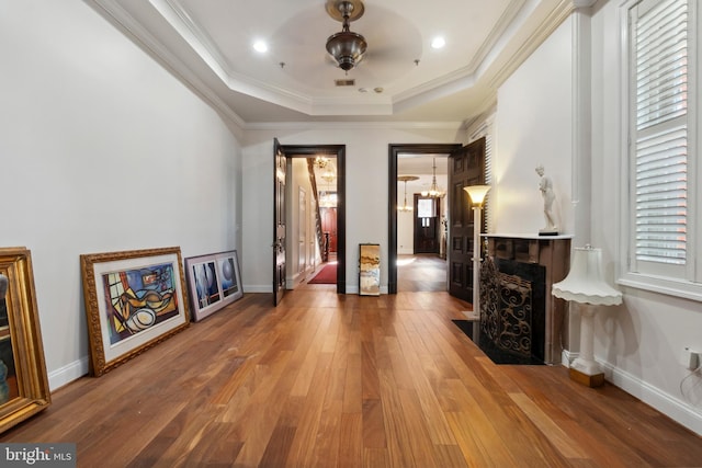 interior space with hardwood / wood-style flooring, ornamental molding, a raised ceiling, and a notable chandelier