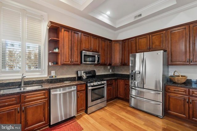 kitchen featuring stainless steel appliances, sink, backsplash, ornamental molding, and light wood-type flooring