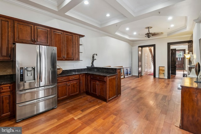 kitchen featuring ceiling fan, stainless steel refrigerator with ice dispenser, kitchen peninsula, wood-type flooring, and dark stone counters