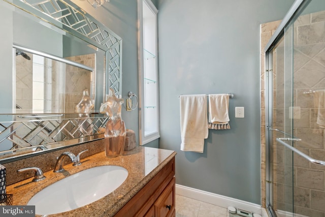 bathroom with a shower with shower door, vanity, and tile patterned flooring