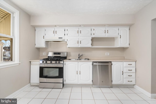 kitchen featuring sink, light tile patterned flooring, appliances with stainless steel finishes, a textured ceiling, and white cabinets