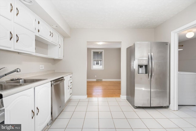 kitchen featuring a textured ceiling, appliances with stainless steel finishes, white cabinetry, and sink