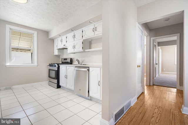 kitchen with white cabinets, a textured ceiling, appliances with stainless steel finishes, and sink