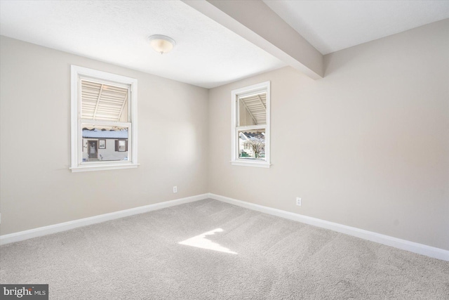 unfurnished room featuring carpet floors and beamed ceiling