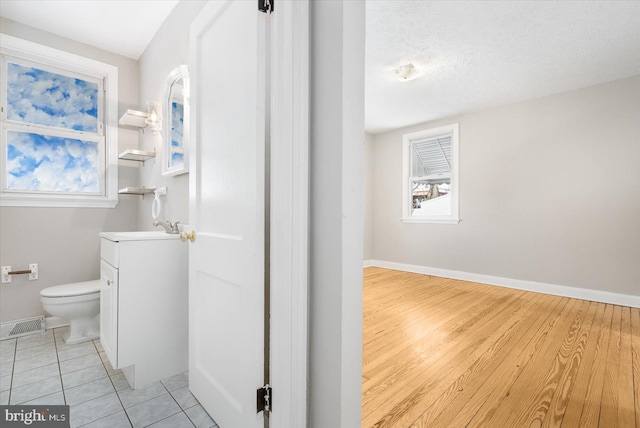 bathroom with tile patterned floors, toilet, vanity, and a textured ceiling