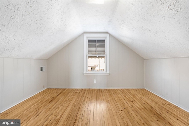 additional living space featuring lofted ceiling and light hardwood / wood-style flooring