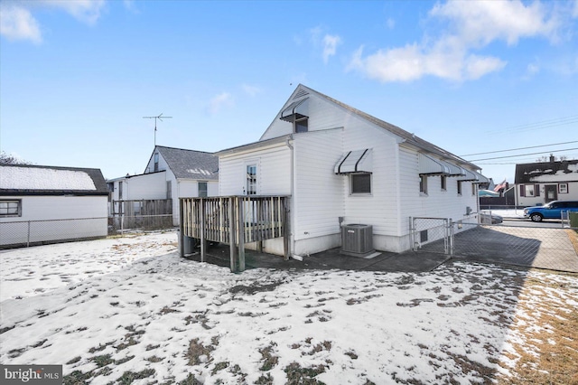 snow covered rear of property featuring central AC unit