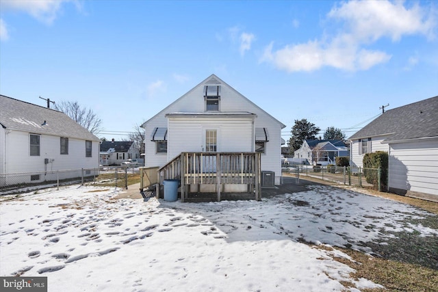 snow covered back of property with central AC unit and a deck