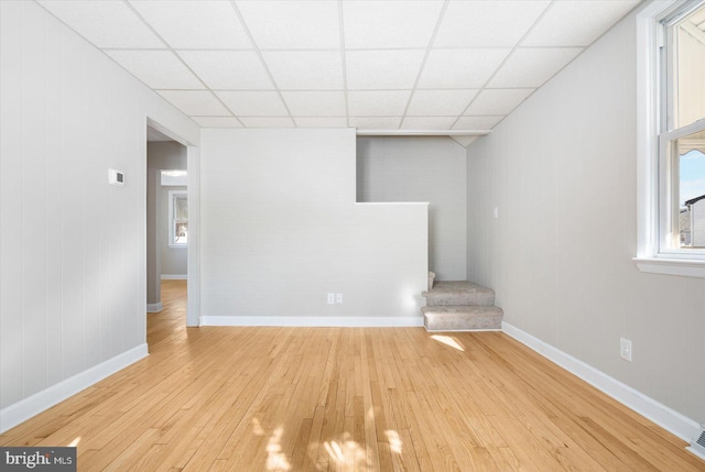 empty room with light wood-type flooring and a drop ceiling