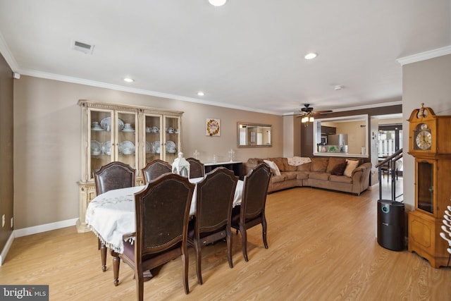 dining space with ceiling fan, light wood-type flooring, and crown molding