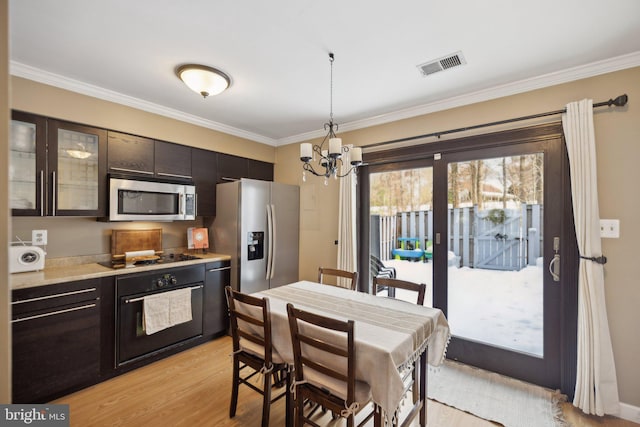 kitchen featuring pendant lighting, black appliances, light hardwood / wood-style floors, a notable chandelier, and crown molding