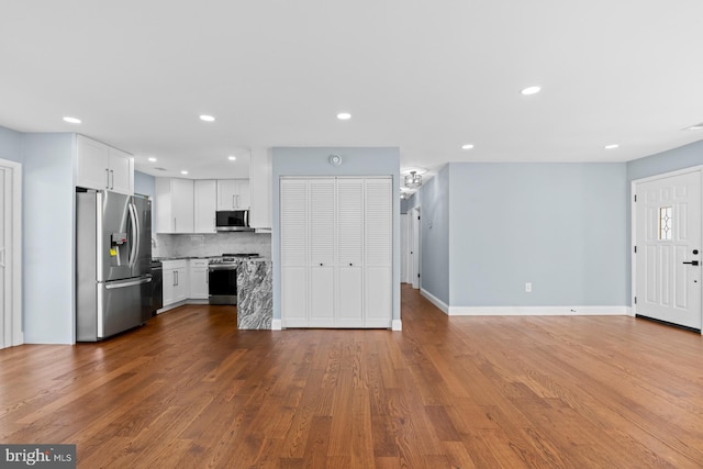 kitchen with hardwood / wood-style flooring, stainless steel appliances, backsplash, and white cabinets