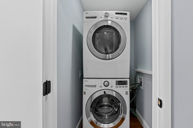 clothes washing area with stacked washer and clothes dryer and dark hardwood / wood-style flooring