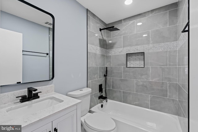 full bathroom featuring toilet, tiled shower / bath, and vanity