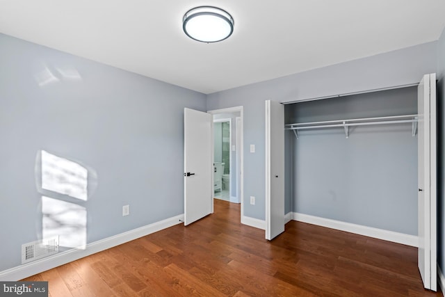 unfurnished bedroom featuring dark hardwood / wood-style floors and a closet