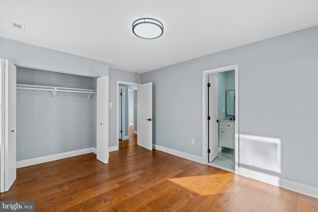 unfurnished bedroom featuring hardwood / wood-style flooring, connected bathroom, and a closet