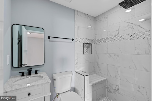 bathroom with toilet, vanity, and tiled shower