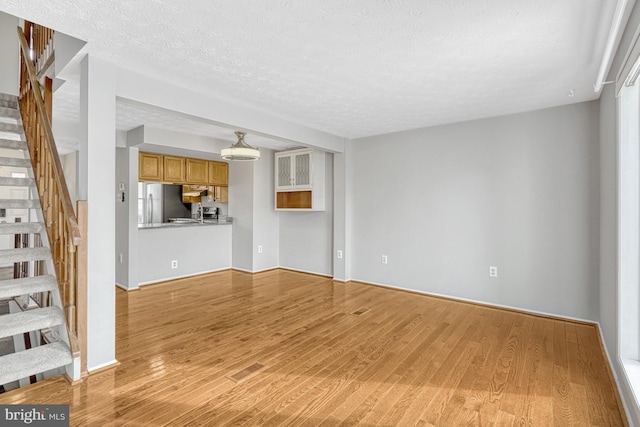 unfurnished living room featuring light hardwood / wood-style floors and a textured ceiling