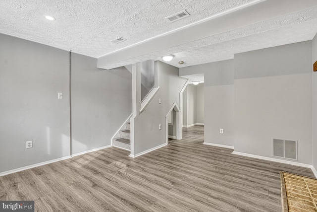 basement with wood-type flooring and a textured ceiling