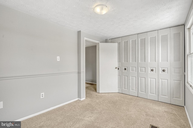 unfurnished bedroom featuring light carpet, a textured ceiling, and a closet