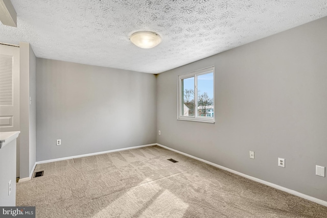 carpeted empty room with a textured ceiling