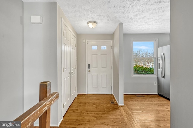 foyer entrance with light hardwood / wood-style floors and a textured ceiling