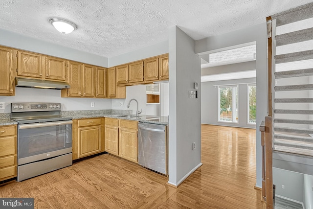 kitchen featuring light hardwood / wood-style flooring, appliances with stainless steel finishes, sink, light stone countertops, and a textured ceiling