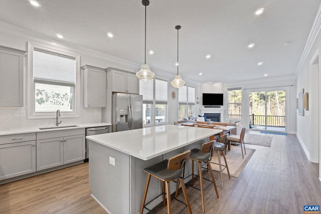 kitchen featuring a kitchen island, sink, gray cabinetry, a breakfast bar area, and stainless steel appliances