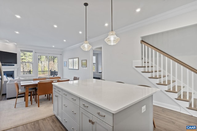 kitchen featuring ornamental molding, light hardwood / wood-style floors, a center island, and decorative light fixtures