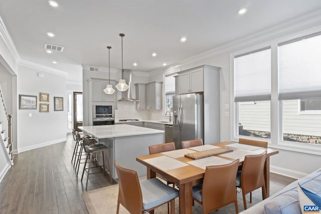 dining space featuring sink, hardwood / wood-style floors, and ornamental molding