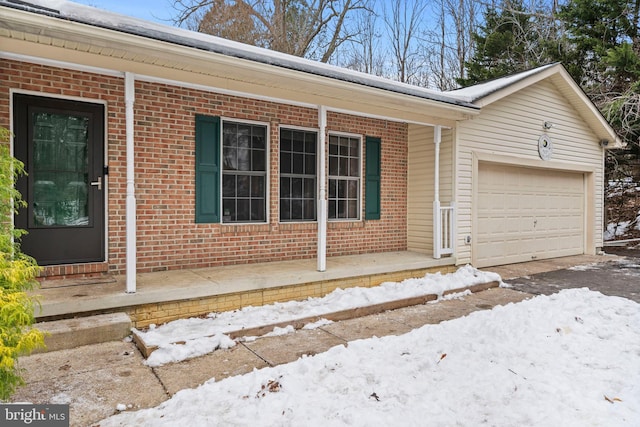 snow covered property entrance featuring a garage