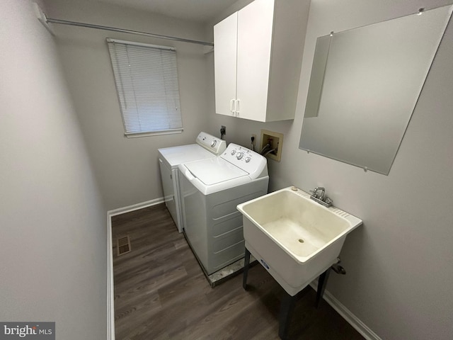 washroom with dark wood-type flooring, cabinets, washing machine and clothes dryer, and sink