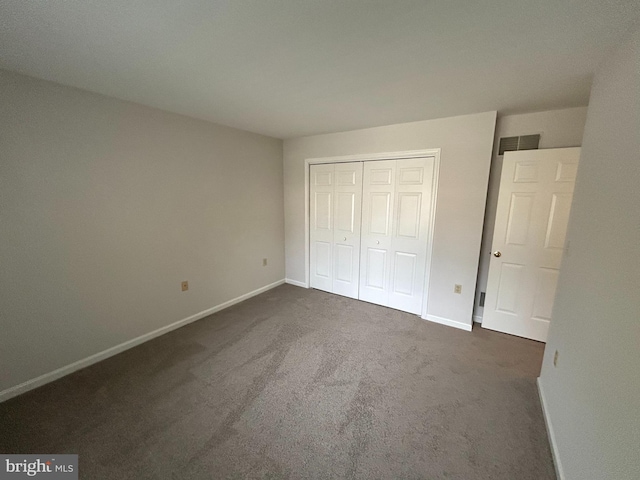 unfurnished bedroom featuring a closet and dark carpet