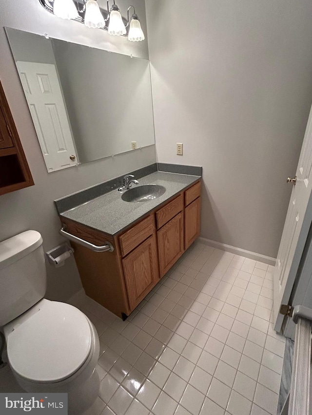 bathroom with toilet, vanity, and tile patterned floors