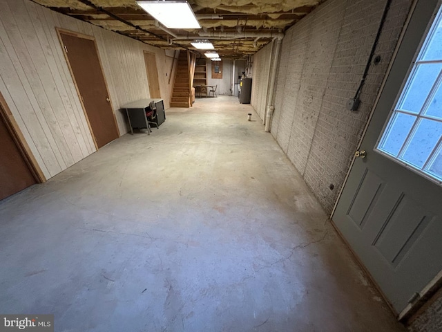 basement featuring wood walls and water heater