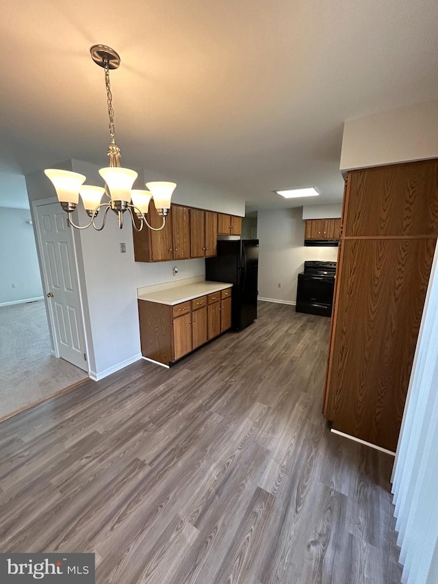 kitchen featuring black appliances, a notable chandelier, dark hardwood / wood-style flooring, and hanging light fixtures