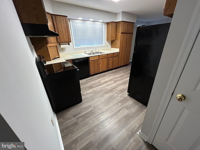 kitchen featuring black appliances, light wood-type flooring, sink, and range hood